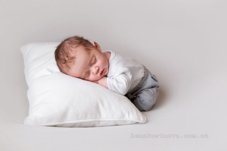 natural style professional photography - Neworn baby wearing white top and grey borrom sleeping on the pillow on the tummy