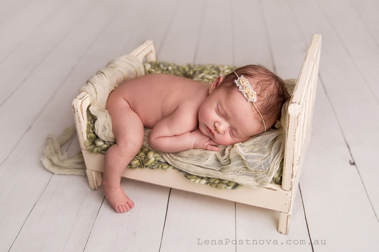 Newborn Photo - gorgeous newborn baby girl sleeping on the tiny bed wearing flower head band