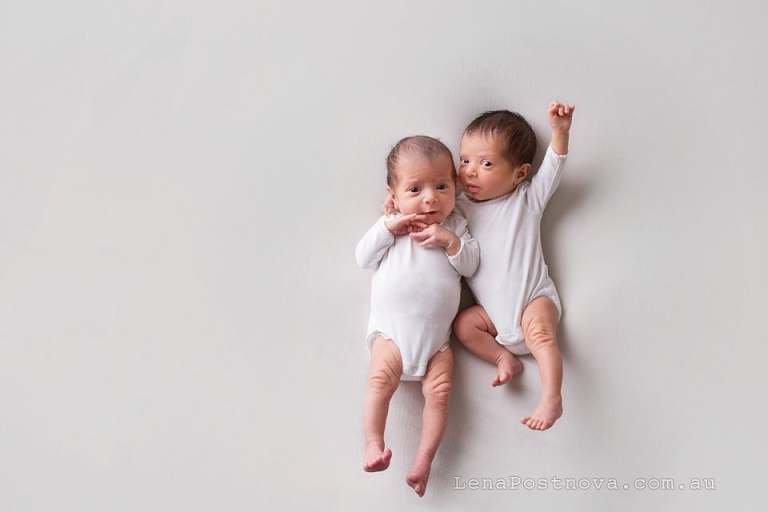 Newborn identical twin girls wearing white onesies