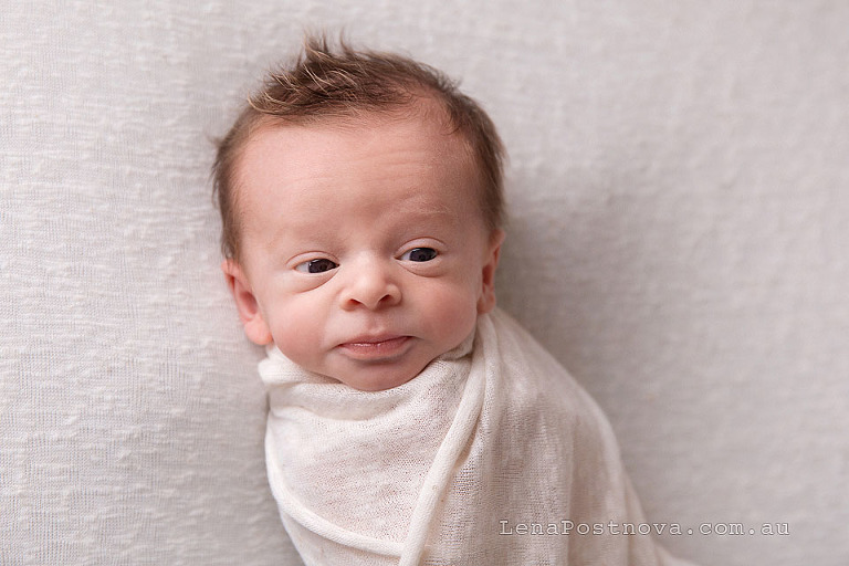 baby boy 2 weeks old awake swaddled in a cream blanket