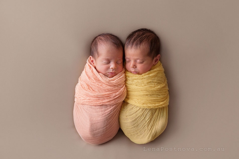 newborn twins 5 weeks old wrapped in orange and yellow wraps 