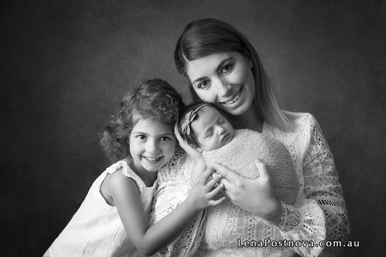 smiling mother with her baby and sibling daughters