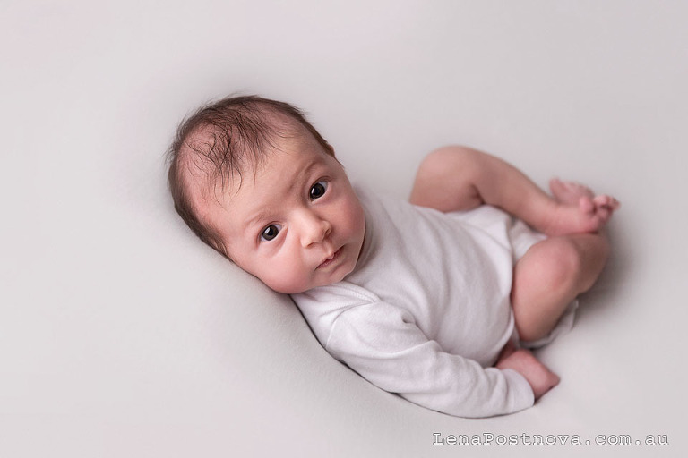 Natural style newborn photos of awake baby girl wearing white romper