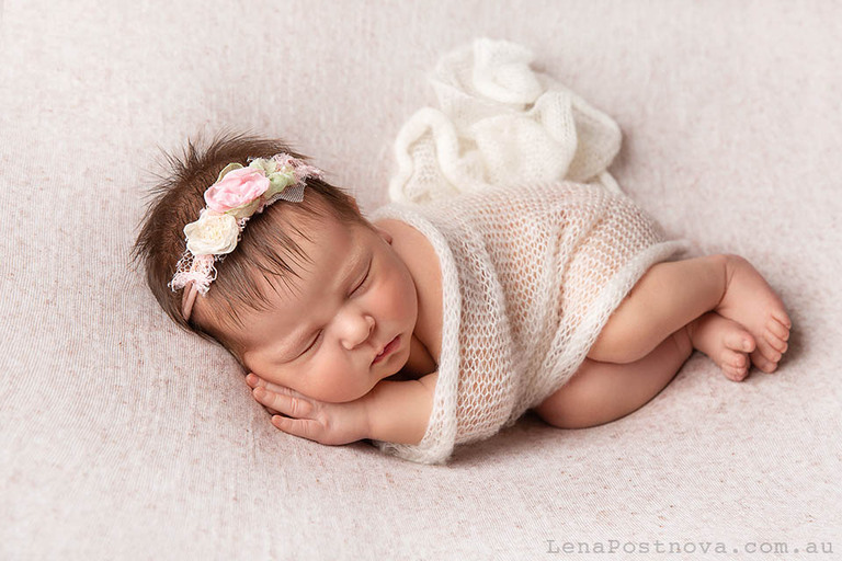 newborn baby girl posed in adorable sleepy pose