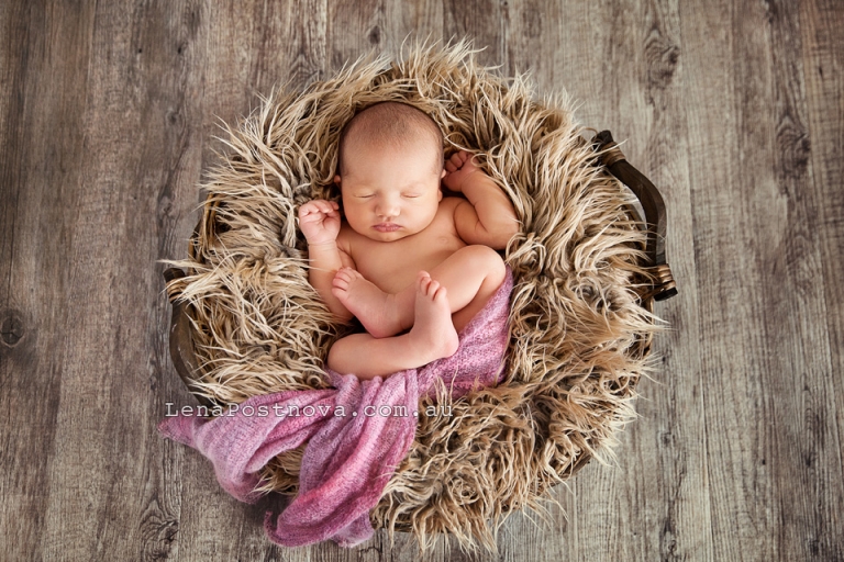 Newborn Baby Girl curled up sleeping in the basket