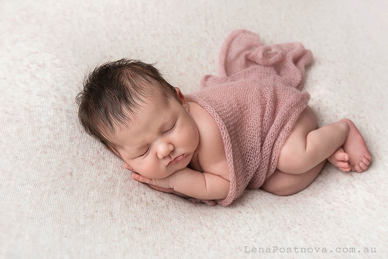 posed newborn baby wearing pink wrap 