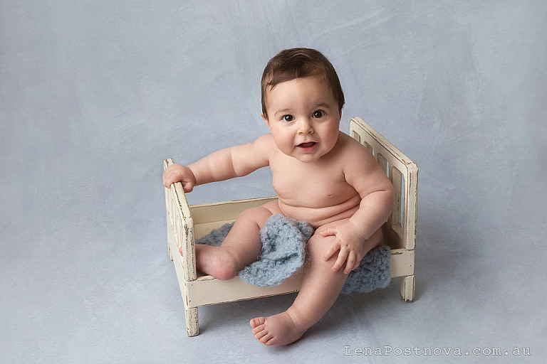 6 months old boy sitting at the tiny bed at his photoshoot baby 