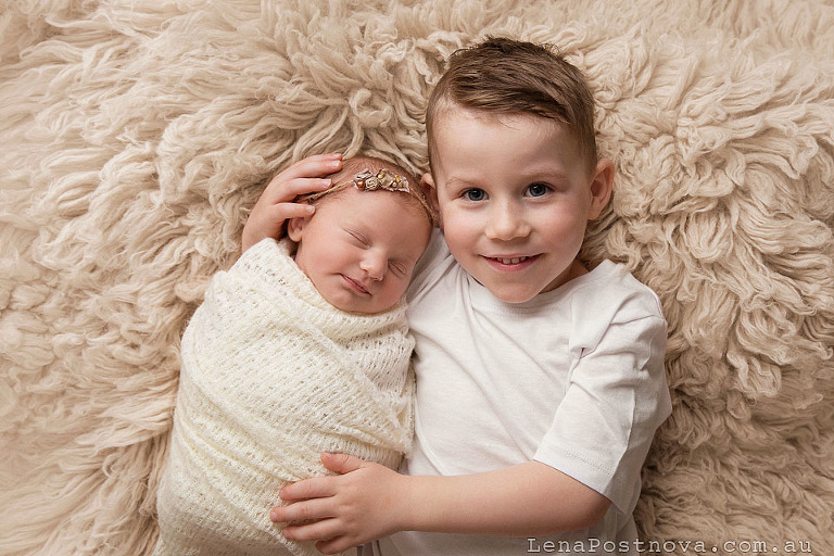 smiling newborn baby girl with her smiling older brother