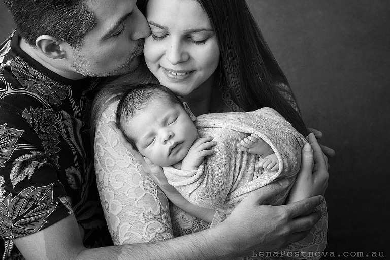 dad kissing mum at newborn photo shoot 